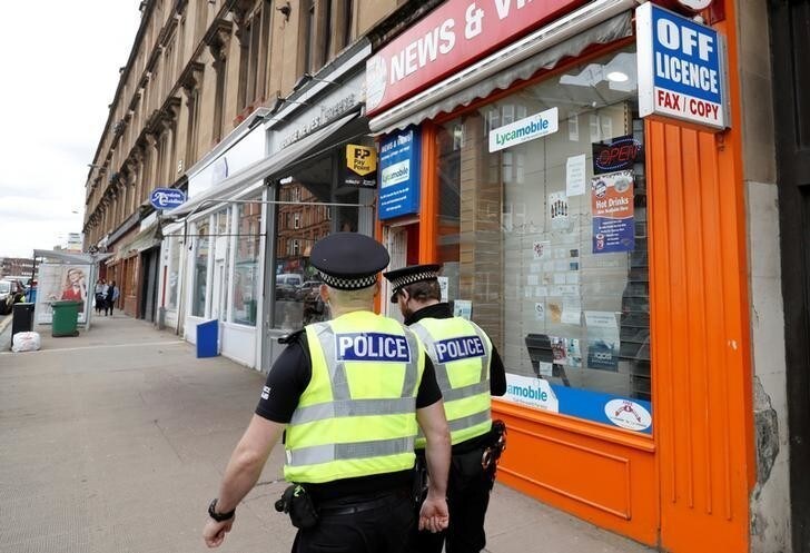 Police officers walk past a shop with a license to sell alcoholic beverages in Glasgow, Scotland, Britain, May 1, 2018. REUTERS/Russell Cheyne