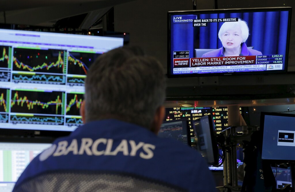 FILE PHOTO: Traders work on the floor of the New York Stock Exchange (NYSE) as a television screen displays coverage of U.S. Federal Reserve Chairmman Janet Yellen, in New York, New York, U.S. December 16, 2015. REUTERS/Lucas Jackson/File Photo - RTX2G64S
