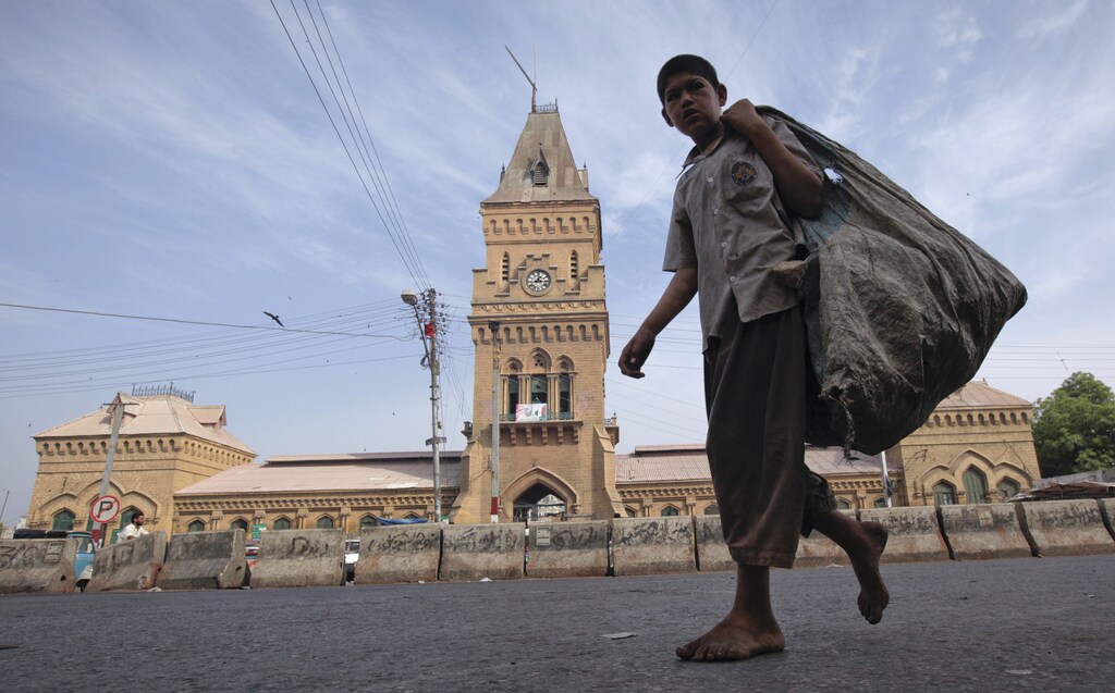 A barefooted boy carries a sack for recyclable materials as he walks past the British era Empress Market building in Karachi April 8, 2012. The Empress Market was constructed between 1884 and 1889 and was named to commemorate Queen Victoria, Empress of India. REUTERS/Akhtar Soomro (PAKISTAN - Tags: SOCIETY BUSINESS EMPLOYMENT ENVIRONMENT) - GM1E848130701