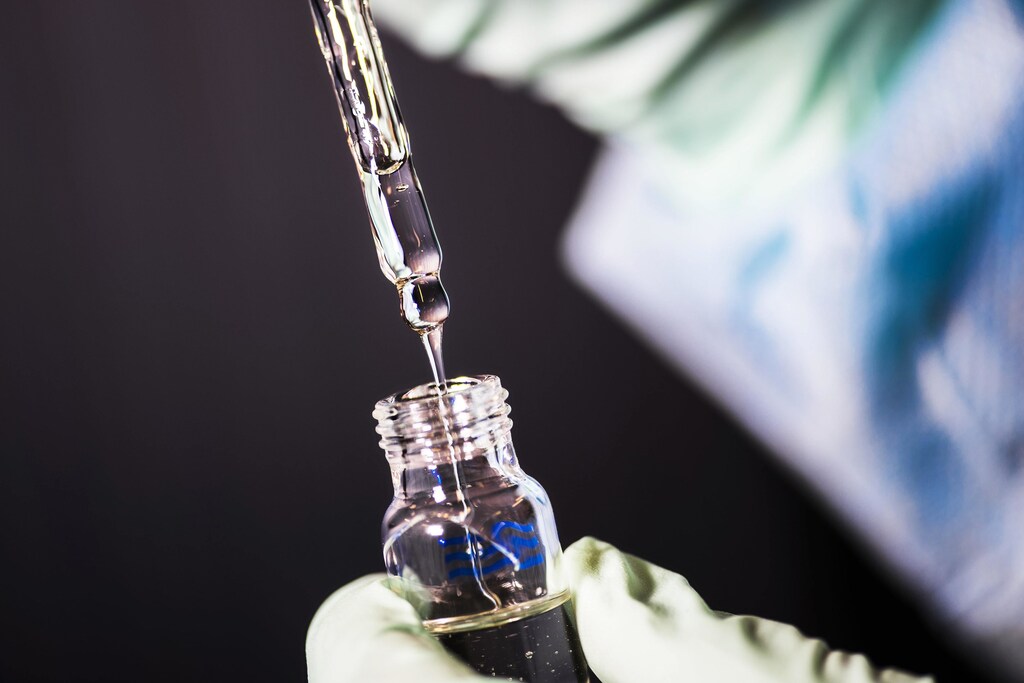 a picture of a scientists taking samples from a medical vile