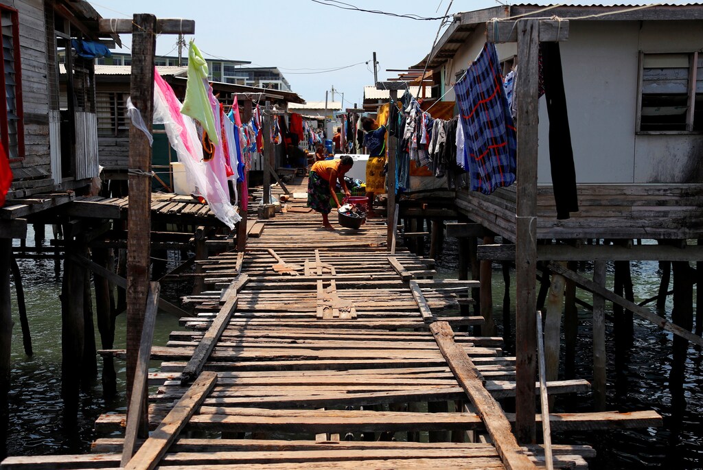 A woman washes clothes on a wooden path between stilt houses at Hanuabada Village, located in Port Moresby Harbour, Papua New Guinea, November 19, 2018. Picture taken November 19, 2018. REUTERS/David Gray - RC1542BE3E00