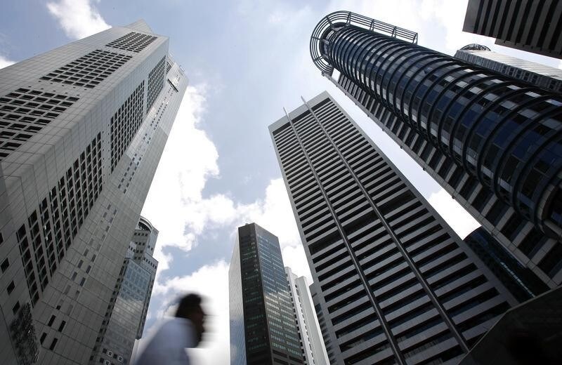 A man walks past buildings at the central business district of Singapore February 14, 2007. Singapore's trade-reliant economy expanded faster than expected in the fourth quarter on a pick up in domestic activity, data showed on Wednesday, prompting the government to lift its expectations for 2007. REUTERS/Nicky Loh (SINGAPORE) - RTR1MDL4
