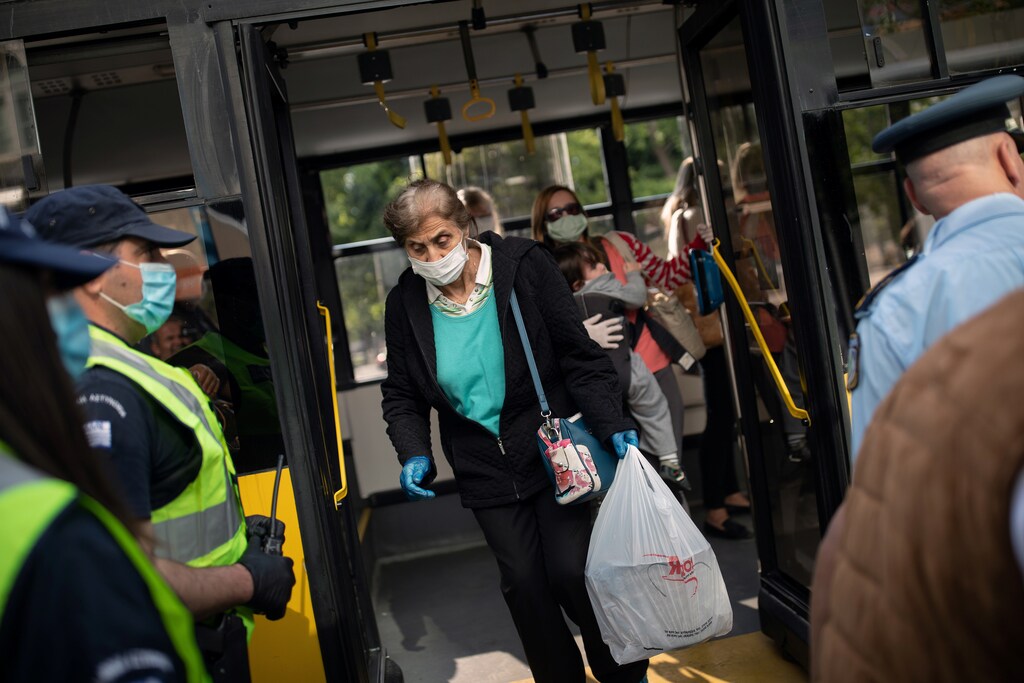 Los agentes de policía esperan para realizar controles a los pasajeros de los autobuses tras el uso obligatorio de mascarillas protectoras, en el primer día de la flexibilización de un bloqueo nacional contra la propagación de la enfermedad coronavirus (COVID-19), en Atenas, Grecia, el 4 de mayo de 2020.