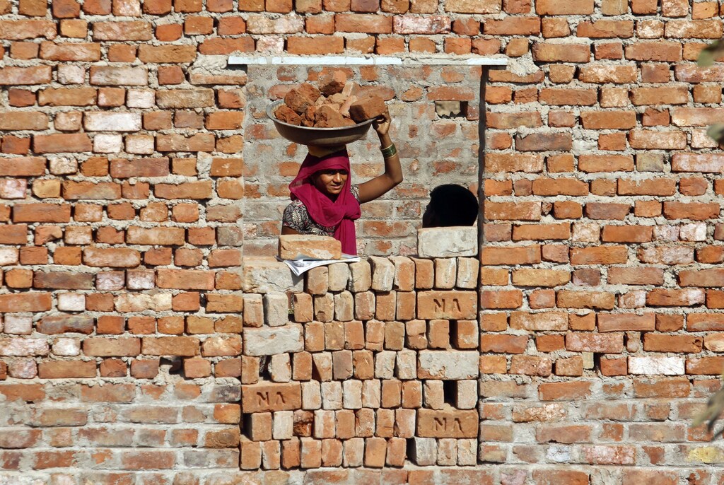 A construction labourer carries bricks on her head at the construction site of a residential estate on the outskirts of the western Indian city of Ahmedabad, November 18, 2011. REUTERS/Amit Dave(INDIA - Tags: SOCIETY BUSINESS EMPLOYMENT CONSTRUCTION) - GM1E7BJ014501