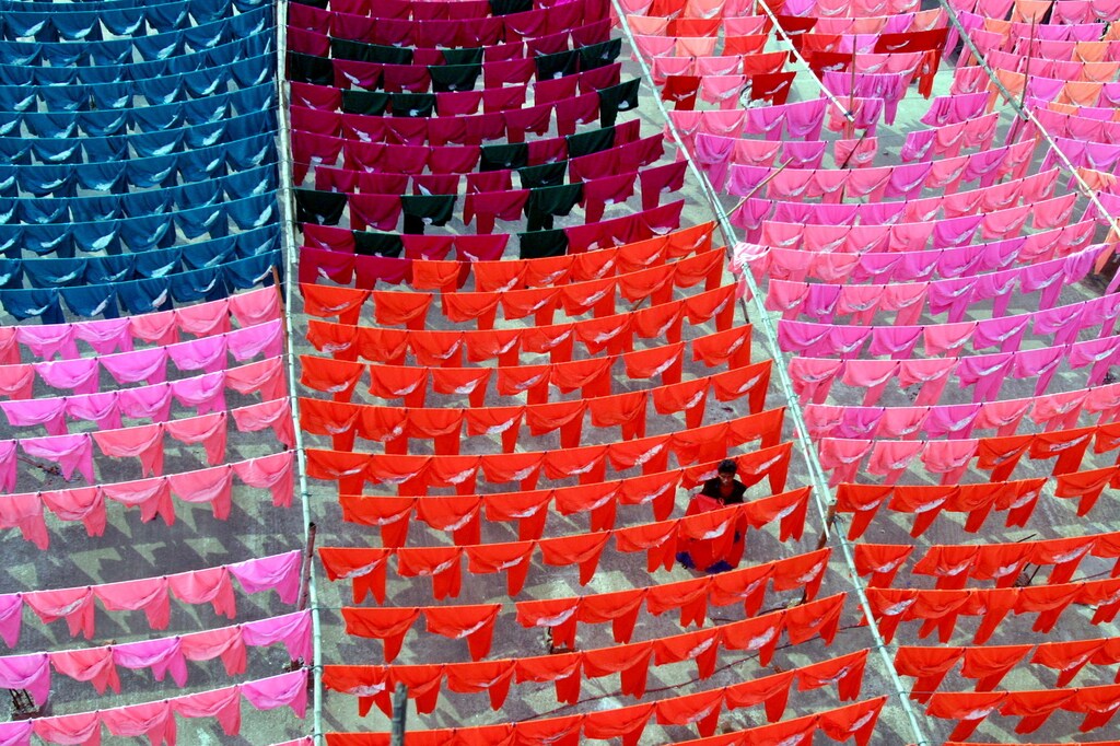 A worker hangs clothes to dry on the roof of a garment factory in the Bangladeshi capital Dhaka on June 15, 2005. Across Bangladesh, hundreds of small clothing factories have closed or slashed jobs following the January expiry of worldwide export quotas allowed under the Multi-Fibre Agreement (MFA), which had regulated the global clothing trade. [Under the MFA, major markets in the United States and Europe guaranteed imports of textiles and garments from poor countries such as Bangladesh and Sri Lanka under a quota system. Picture taken June 15, 2005.] - PBEAHUNZBDB