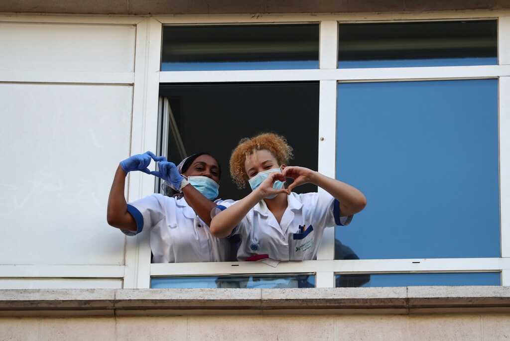 Medical staff from Fundacion Jimenez Diaz hospital make a heart gesture with their hands, while people applaud from their balconies in support for healthcare workers, as it is expected to be the last day of applauses, amid the coronavirus disease (COVID-19) outbreak, in Madrid, Spain, May 17, 2020
