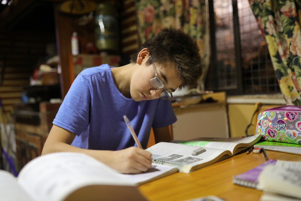 a teenager sits doing his homework