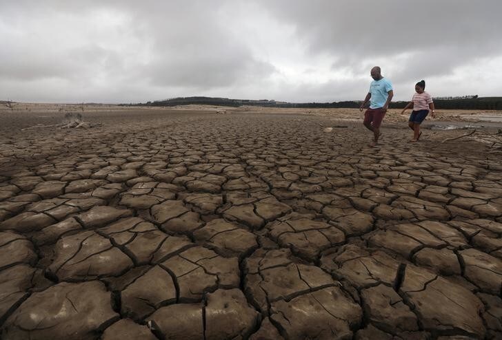 A family negotiates their way through caked mud around a dried up section of the Theewaterskloof dam near Cape Town, South Africa, January 20, 2018. The dam, which supplies most of Cape Town's potable water, is currently dangerously low as the city faces "Day Zero", the point at which taps will be shut down accross the city. Picture taken January 20, 2018. REUTERS/Mike Hutchings