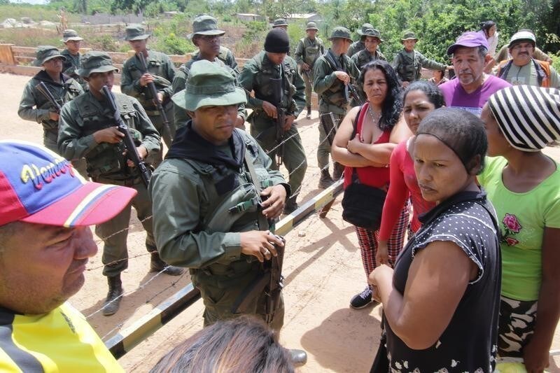People stand next to Venezuelan soldiers, as they wait for information about the deaths in a remote illegal mine where seven people were killed, according to family members, near the Tarabay military base in Tumeremo, Venezuela October 17, 2018.