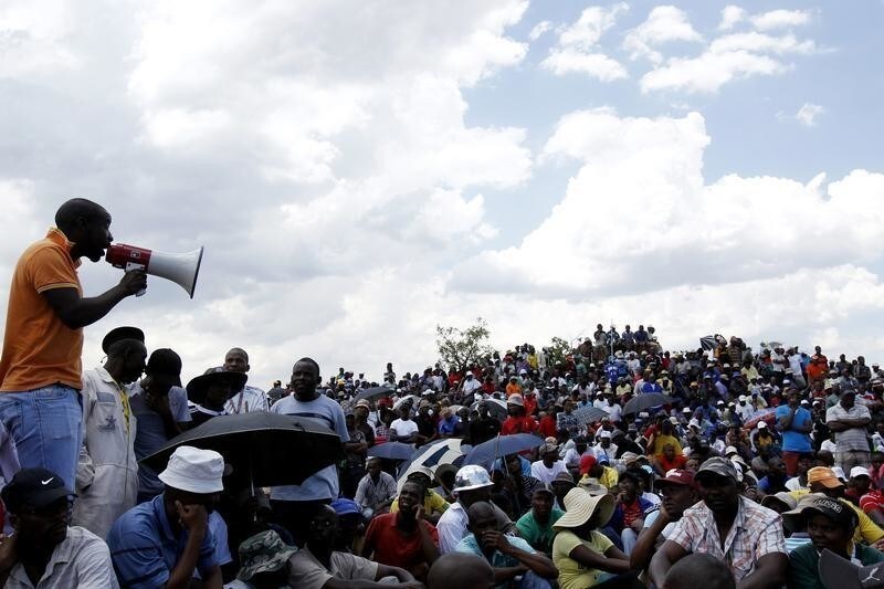 Striking miners listen to an address by their leader at the AngloGold Ashanti mine in Carletonville, northwest of Johannesburg October 19, 2012. South African workers officially ended a month-long strike at major bullion producer Gold Fields on Friday but there was still no end in sight for wildcat walkouts that have paralysed other gold and platinum producers. More than 80,000 miners have downed tools in the resource-rich country since August in often violent strikes over pay and working conditions that are hitting growth and investor confidence in Africa's biggest economy and raising questions about President Jacob Zuma's leadership.
