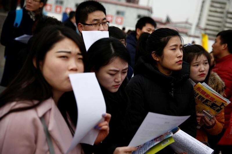Job seekers look at offers at an open air job fair for college graduates and the general public in the centre of Shijiazhuang, Hebei province, China, February 6, 2017. REUTERS/Thomas Peter - RTX2ZS3N