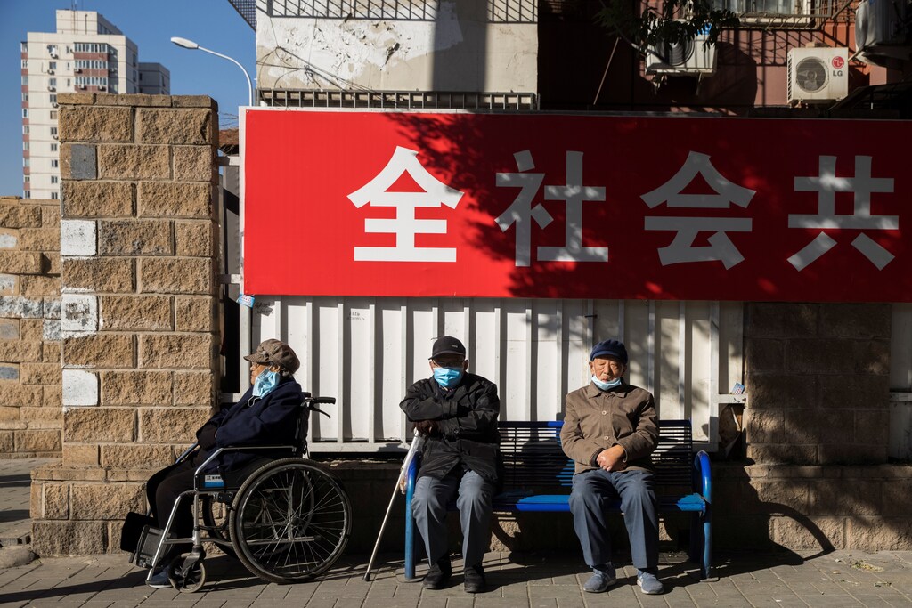 Elderly people sit in a street during morning rush hour following an outbreak of the coronavirus disease (COVID-19) in Beijing, China, November 3, 2020. REUTERS/Thomas Peter - RC2GVJ9NU878