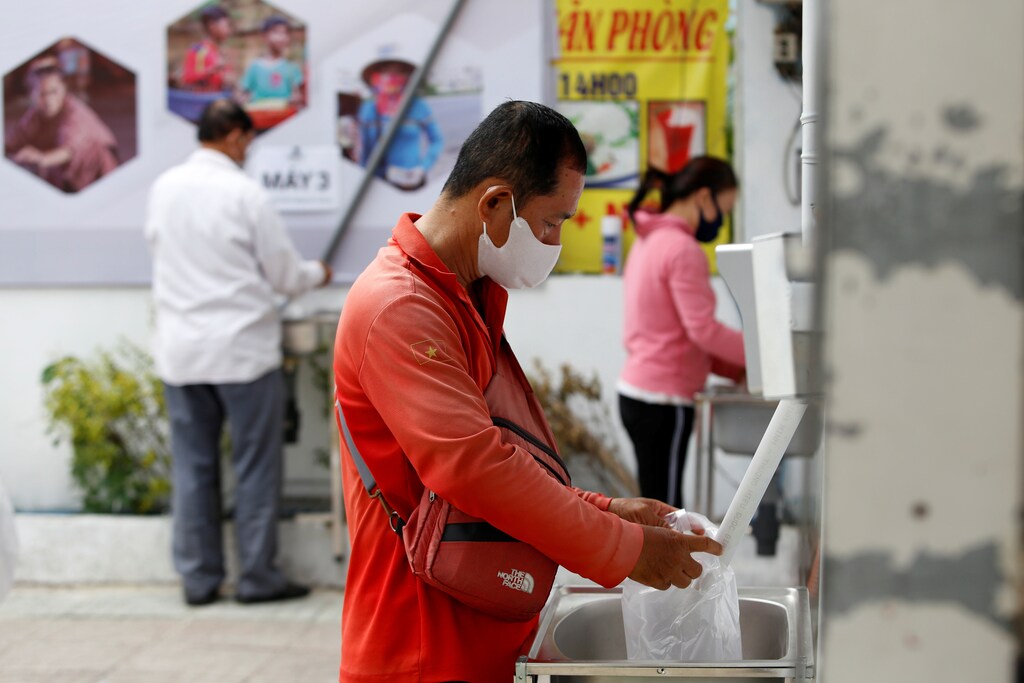 People get rice from a 24/7 automatic rice dispensing machine, 'Rice ATM', during the outbreak of the coronavirus disease (COVID-19), in Ho Chi Minh, Vietnam, April 11, 2020. Picture taken April 11, 2020. REUTERS/Yen Duong - RC2I3G9U37O1
