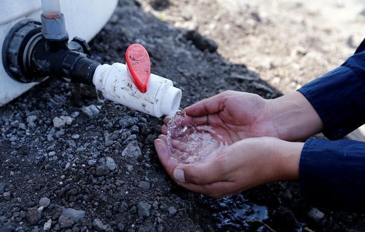 A worker checks water collection from nets, set up by a group of community leaders called 'Peruvians Without Water', used to trap water from the moisture in fog, on the hillside of Villa Maria Del Triunfo in Lima, Peru, May 11, 2016. REUTERS/Mariana Bazo