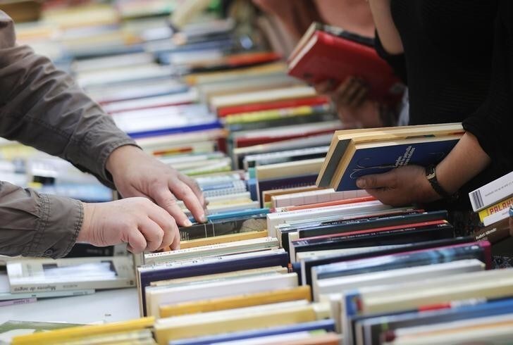 People look books in a stand at Las Ramblas street during traditional Sant Jordi's day celebrations in Barcelona April 23, 2014. Sant Jordi is the patron saint of Catalonia and traditionally, the man gives a rose to his girl and she gives him a book. REUTERS/Albert Gea (SPAIN - Tags: SOCIETY)
