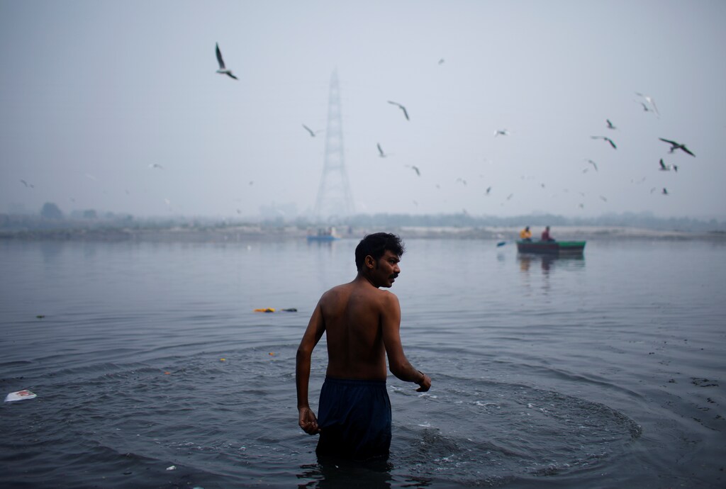 A man bathes in the Yamuna river on a smoggy morning in New Delhi, India, November 4, 2021: Standards, monitoring and enforcement can help industries comply and reduce river pollution