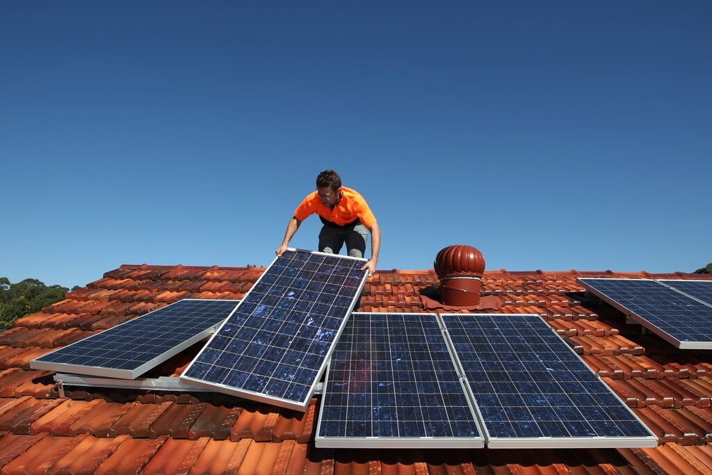 Solar system installer Thomas Bywater adjusts new solar panels on the roof of a house in Sydney August 19, 2009. REUTERS/Tim Wimborne (AUSTRALIA ENVIRONMENT ENERGY) - GM1E58J161901