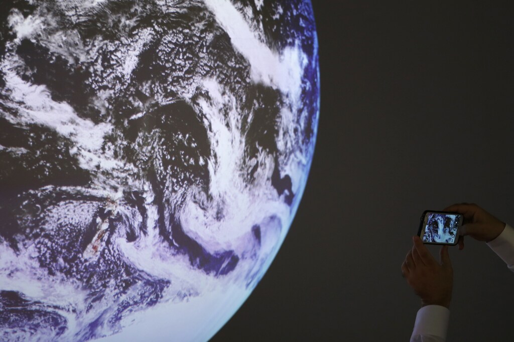 A participant takes a picture of a replica of the Planet during the World Climate Change Conference 2015 (COP21) at Le Bourget, near Paris, France.
