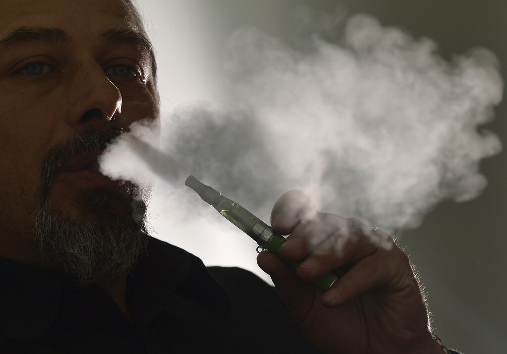 Gabor Kovacs of 'smoke no smoke' puffs on an e-cigarette that his shop sells at Camden in London June 9, 2013. Puffing on slim metal tubes loaded with pale yellow liquid, two London businessmen say they have between their lips a cure for what the U.N. calls "one of the biggest public health threats the world has ever faced". Electronic cigarettes are the future, they argue. Cheaper, cleaner and cooler than smoking, "vaping" - using a vaporiser to inhale nicotine infused with exotic flavours ranging from pina colada to bubblegum - will spell the end of tobacco. Picture taken June 9, 2013. To match Insight HEALTH-ECIGARETTES/ REUTERS/Toby Melville (BRITAIN - Tags: BUSINESS HEALTH SOCIETY) - GM1E96D1K8301