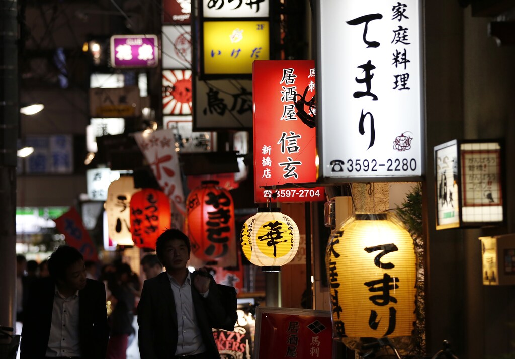 People walk past signboards of restaurants at Tokyo's business district October 17, 2014. Nearly half of Japanese firms think the government should start defending the yen at this month's dollar high of 110, a Reuters survey shows, underscoring the threat that rising fuel and other import costs pose to a fragile economy. Picture taken October 17, 2014. REUTERS/Yuya Shino (JAPAN - Tags: BUSINESS EMPLOYMENT) - GM1EAAK036T01