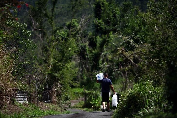 A man carries ice and water distributed by municipal workers and provided by the U.S. Federal Emergency Management Agency (FEMA), after Hurricane Maria hit the island in September 2017, in Comerio, Puerto Rico January 31, 2018. Picture taken January 31, 2018. REUTERS/Alvin Baez