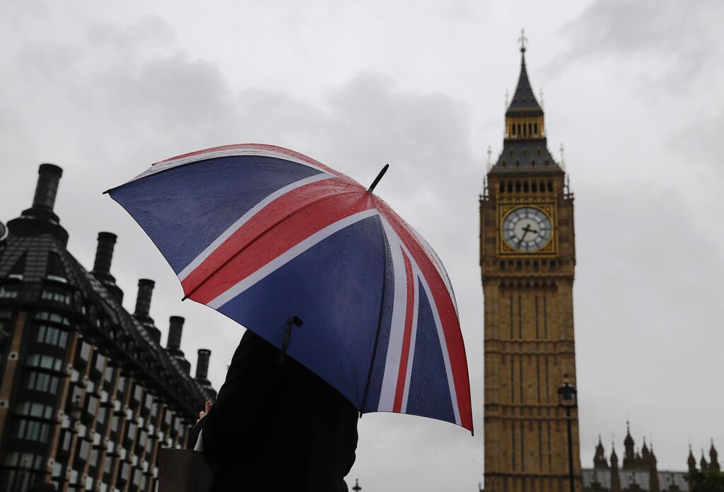 A woman holds a Union flag umbrella in front of the Big Ben clock tower (R) and the Houses of Parliament in London October 4, 2014. REUTERS/Luke MacGregor (BRITAIN - Tags: ENVIRONMENT CITYSCAPE TRAVEL) - RTR48XA7