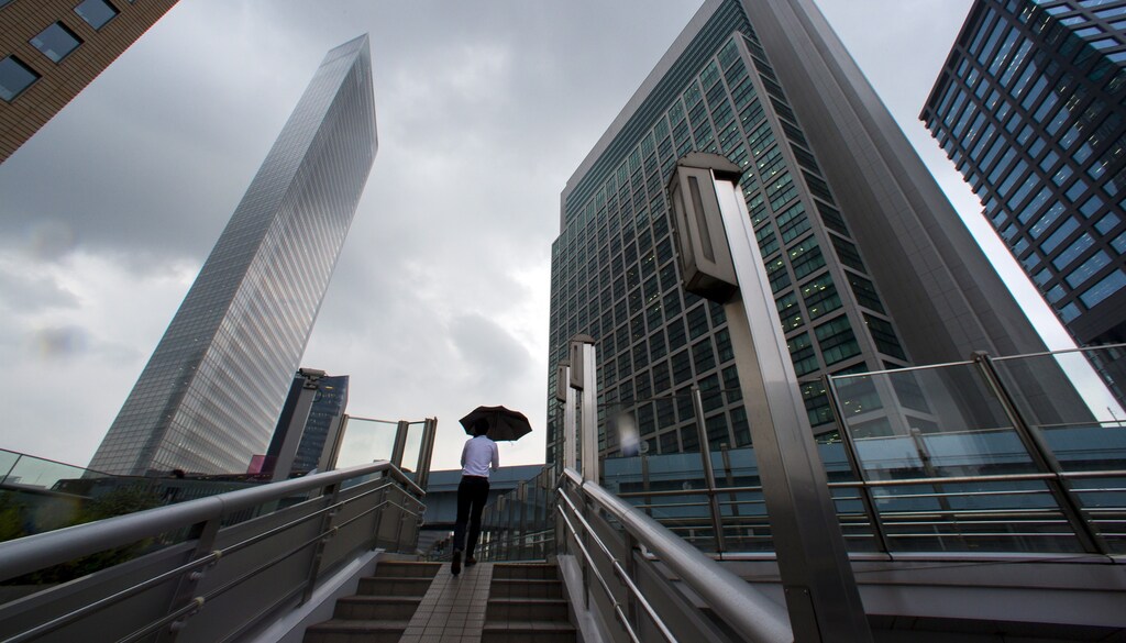 A man walks in the shadows of office skyscrapers in a business district in Tokyo August 20, 2015.