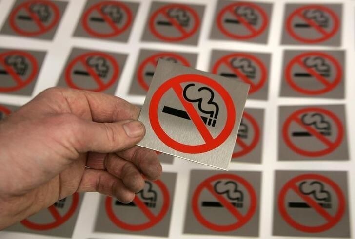 A printer lays a no smoking sign alongside others at First Safety Signs in Bishops Stortford in eastern England, June 29, 2007. With a ban on smoking in all enclosed public spaces coming into force in England on July 1, 2007 analysts predict nightclubs, casinos and bingo firms will be hardest hit while restaurants will be the biggest beneficiaries. REUTERS/Luke MacGregor (BRITAIN)