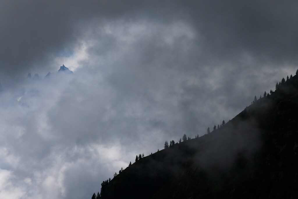Clouds are seen between peaks and trees in Emosson, Switzerland August 9, 2017. REUTERS/Denis Balibouse - RC13053E6BD0