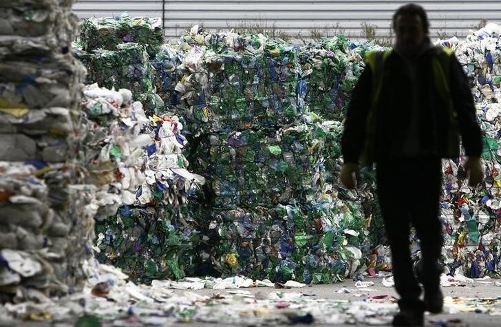 A man walks through bundles of bottles waiting to be recycled at the Closed Loop recycling plant in Dagenham, east London February 17, 2009. Supermarkets should be made to pay more for the food packaging waste they create, local councils said on Tuesday, after a survey found almost 40 percent of it was hard to recycle. REUTERS/Luke MacGregor (BRITAIN)
