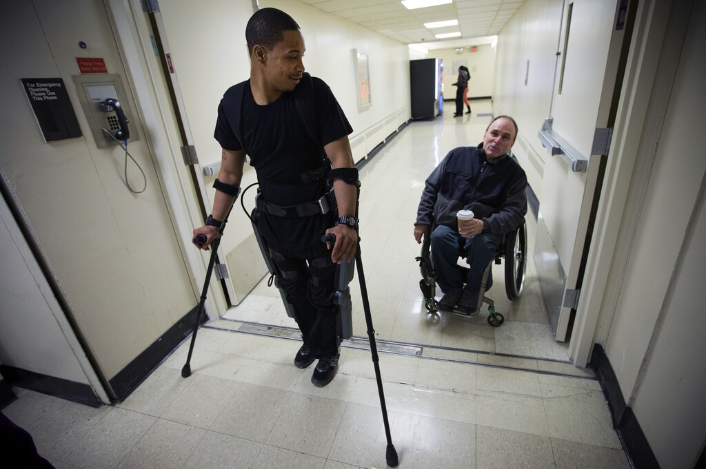 22-year-old Errol Samuels from Queens, New York, who lost the use of his legs in 2012 after a roof collapsed onto him at an off-campus house party near where he was attending college in upstate New York, pauses while walking with a ReWalk electric powered exoskeletal suit to talk to Jim Cesario (R), Spinal Chord Injury Outreach Coordinator, during a therapy session with the ReWalk at the Mount Sinai Medical Center in New York City March 26, 2014. Made by the Israeli company Argo Medical Technologies, ReWalk is a computer controlled device that powers the hips and knees to help those with lower limb disabilities and paralysis to walk upright using crutches. Allan Kozlowski, assistant professor of Rehabilitation Medicine at Icahn School of Medicine at Mount Sinai hospital, where patients like Samuels are enrolled in his clinical trials of the ReWalk and another exoskeleton, the Ekso (Ekso Bionics) hopes machines like these will soon offer victims of paralysis new hope for a dramatically improved quality of life and mobility. The ReWalk is currently only approved by the U.S. Food and Drug Administration (FDA) for use in rehabilitation facilities like at Mount Sinai, as they weigh whether to approve the device for home use as it already is in Europe. Picture taken March 26, 2014. REUTERS/Mike Segar (UNITED STATES - Tags: SCIENCE TECHNOLOGY HEALTH BUSINESS) - GM1EA3S1RU901