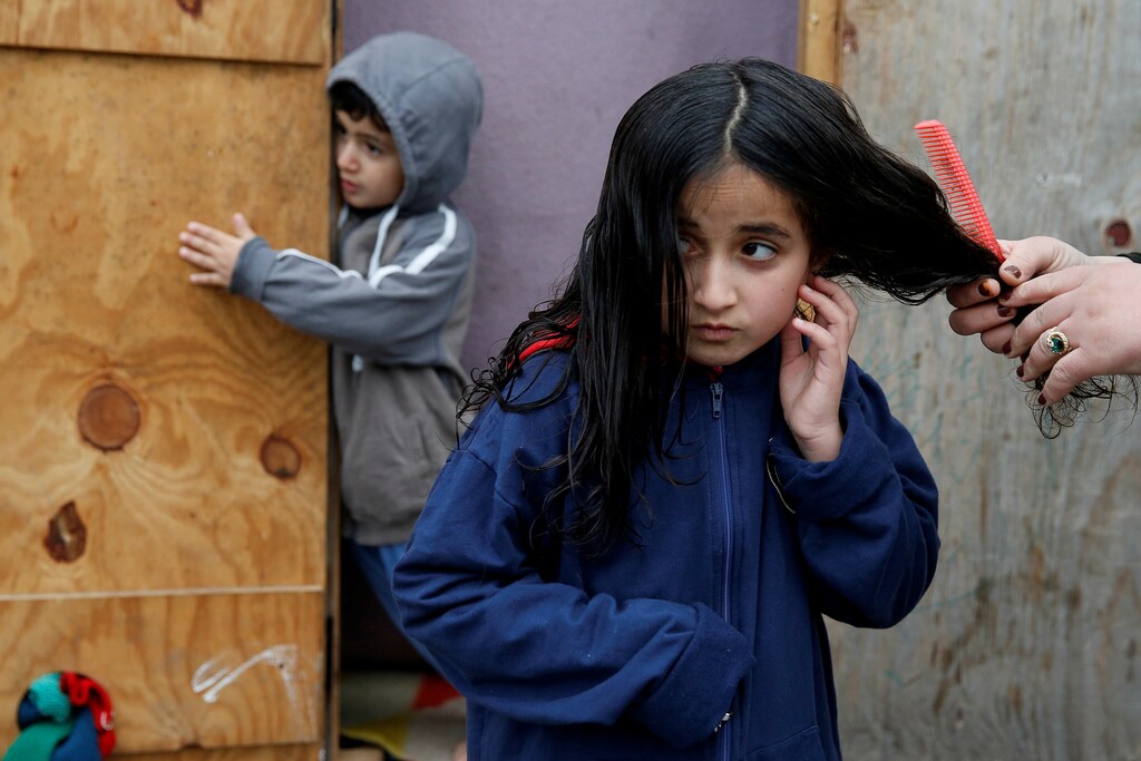 On the eve of International Migrants Day by United Nations, Lia, a Kurdish girl from Iraq, has her hair brushed by her mother at a camp for migrants in Grande Synthe, France December 17, 2016. REUTERS/Pascal Rossignol - RTX2VH09