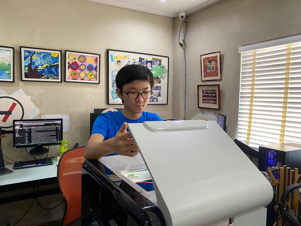 Filipino student Marcus Chu lifts the lid of his 3D printer while working on printing frames for his face shields at his home in Manila, Philippines, April 1, 2020. Picture taken April 1, 2020. GIFFORD CHU/Handout via REUTERS. THIS IMAGE HAS BEEN SUPPLIED BY A THIRD PARTY. MANDATORY CREDIT - RC22WF947POS