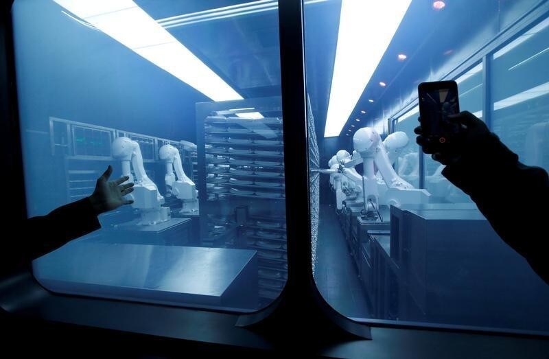 A customer takes a picture as robotic arms collect pre-packaged dishes from a cold storage, done according to the diners' orders, at Haidilao's new artificial intelligence hotpot restaurant in Beijing, China, November 14, 2018. Picture taken November 14, 2018. REUTERS/Jason Lee TPX IMAGES OF THE DAY - RC14D8976800