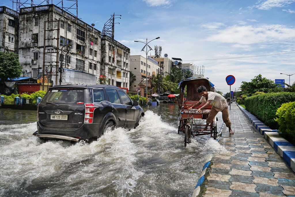 インド西ベンガル州コルカタ。浸水した道路を車と人が通っている。