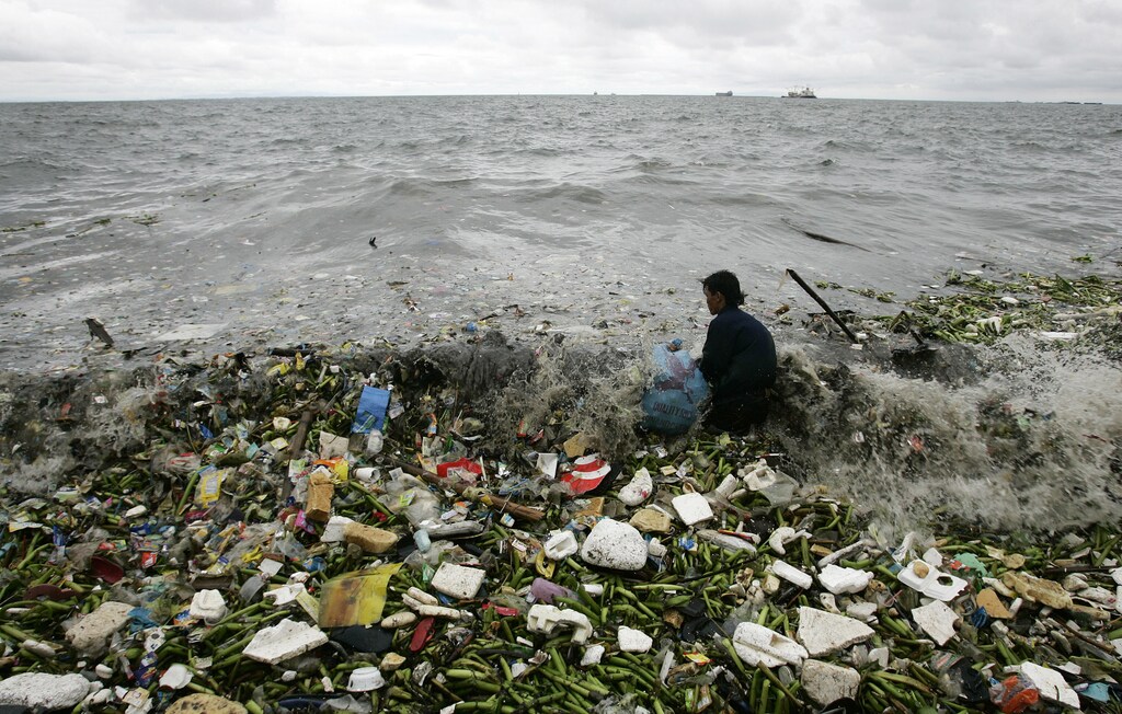 A man collects recyclable plastic materials, washed ashore by waves, which will be sold for 21 pesos ($0.48) in exchange for food in Manila August 2, 2008. REUTERS/Cheryl Ravelo (PHILIPPINES) - RTR20K6N