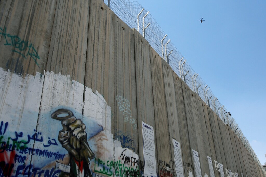An U.S. helicopter flies over a section of the Israeli barrier in the West Bank town of Bethlehem, a day before Trump's planned visit to the town, May 22, 2017. REUTERS/Mussa Qawasma - RTX370JF