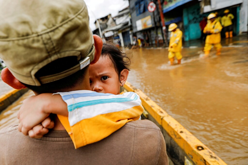A girl is carried by her father across floodwaters in the Jatinegara area after heavy rains in Jakarta, Indonesia, January 2, 2020.