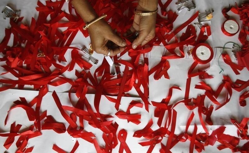 A volunteer suffering from HIV/AIDS makes AIDS symbols with red ribbons during a vaccination programme organised by a non-government organisation 'Sngobadho' (Together) at their office on the outskirts of the northeastern Indian city of Siliguri August 5, 2008. India is failing to provide basic healthcare to its poorest children despite robust economic growth, underlining a widening gap between rich and poor across the Asia-Pacific region, the United Nations said on Tuesday. Experts say many of the two-thirds of Indians living in rural areas do not have access to basic medical facilities, despite the country achieving 9 percent economic growth. REUTERS/Rupak De Chowdhuri (INDIA) - RTR20NGR