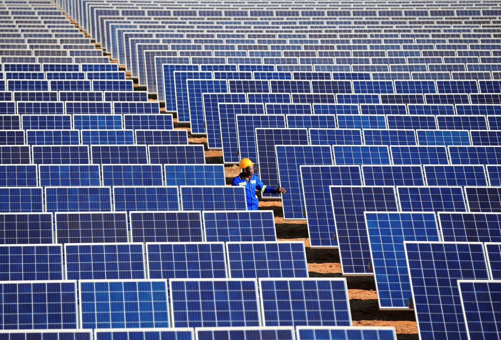 A worker walks between solar panels at Centragrid power plant in Nyabira, Zimbabwe, June 23, 2020. REUTERS/Philimon Bulawayo - RC2XEH95PCV2