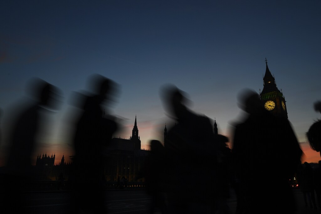 People cross Westminster Bridge as dusk falls behind the Houses of Parliament on a clear evening in central London, Britain December 5, 2016. REUTERS/Toby Melville - RTSURJT