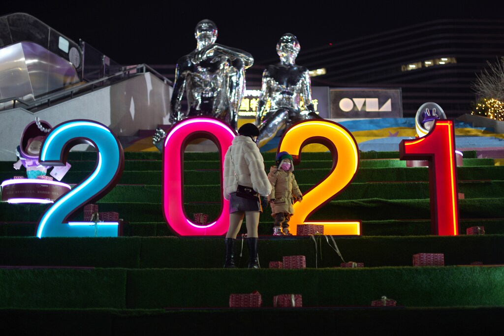 A child wearing a mask plays next to a numeral installation showing 2021, at a shopping complex in Beijing, China.