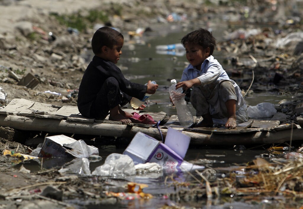 two boys play among some plastic pollution