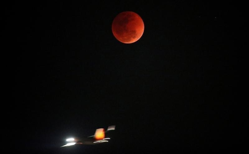 A lunar eclipse of a full "Blue Moon" is seen as an airplane passes by in Ahmedabad, India, January 31, 2018.