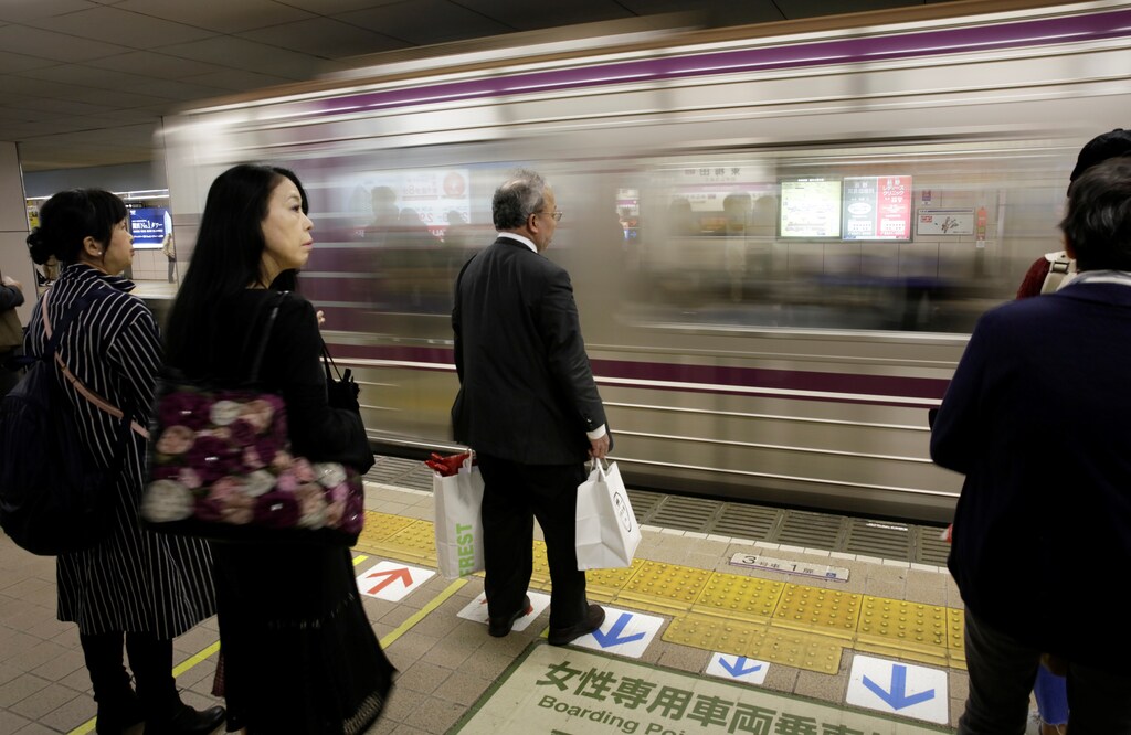 Commuters and an office worker wait for a train in Osaka, western Japan October 24, 2017. Picture taken October 24, 2017. REUTERS/Thomas White GLOBAL BUSINESS WEEK AHEAD SEARCH GLOBAL BUSINESS 30 OCT FOR ALL IMAGES - RC136F687FF0