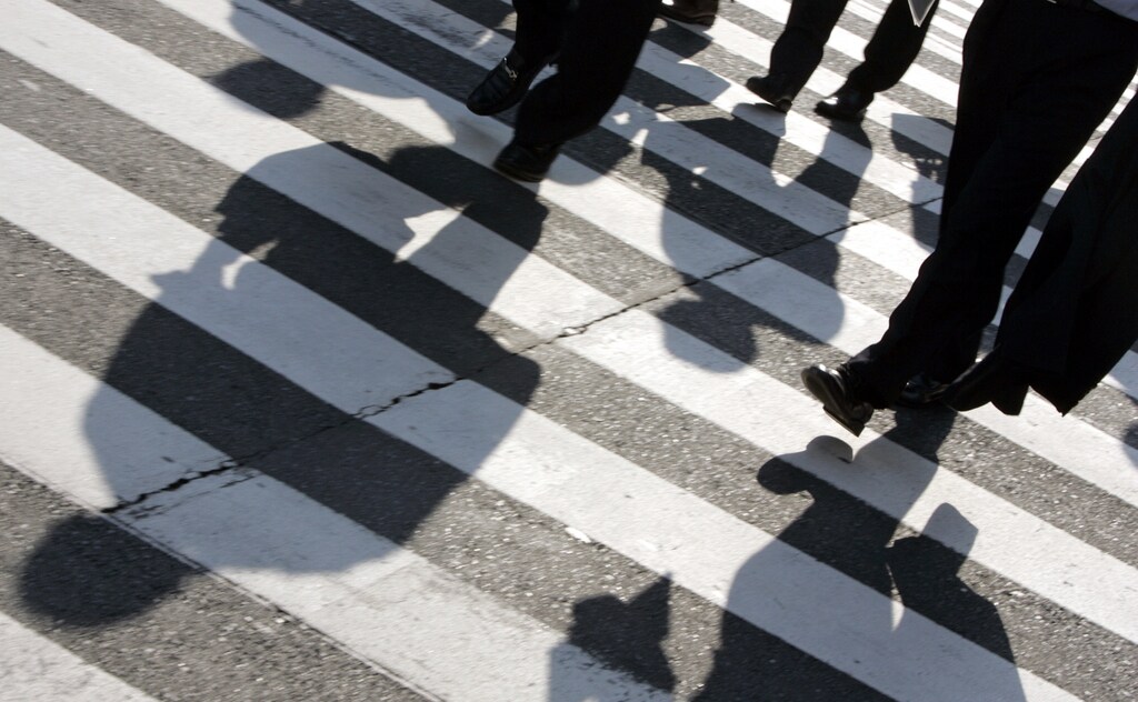 Businessmen cast shadows as they cross a street in Tokyo's Marunouchi district.