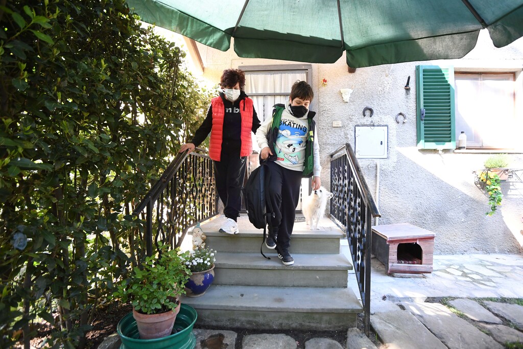 Giulio Giovannini, 12, together with his mother Gloria, a backpack and a tablet, leaves the house to travel from his family cottage in the Tuscan countryside, where he has no internet signal, to the top of a hill where he is able to access the Internet to participate in online lessons while schools remain closed due to the spread of coronavirus disease (COVID-19), in Scansano, Italy, April 15, 2020. REUTERS/Jennifer Lorenzini - RC205G9FAPHB
