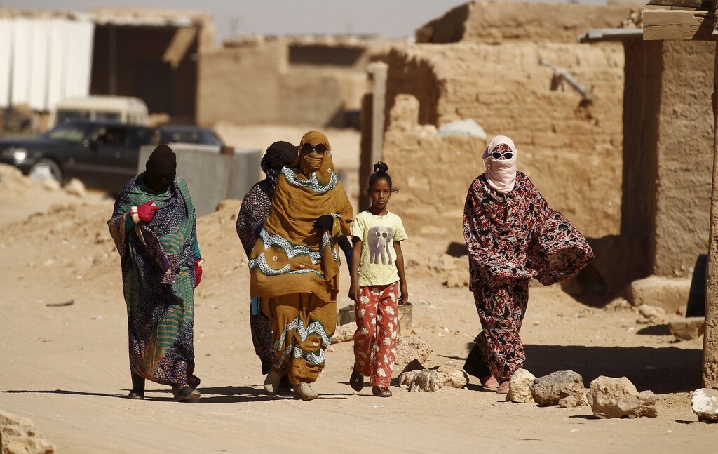 Indigenous Sahrawi women walk through Al Smara desert refugee camp in Tindouf, southern Algeria March 4, 2016. In refugee camps near the town of Tindouf in arid southern Algeria, conditions are hard for indigenous Sahrawi residents. Residents use car batteries for electricity at night and depend on humanitarian aid to get by. The five camps near Tindouf are home to an estimated 165,000 Sahrawi refugees from the disputed region of Western Sahara, according to the United Nations refugee agency UNHCR. REUTERS/Zohra Bensemra SEARCH "THE WIDER IMAGE" FOR ALL STORIES Matching text ALGERIA-SAHARA/ - RTS9CD3