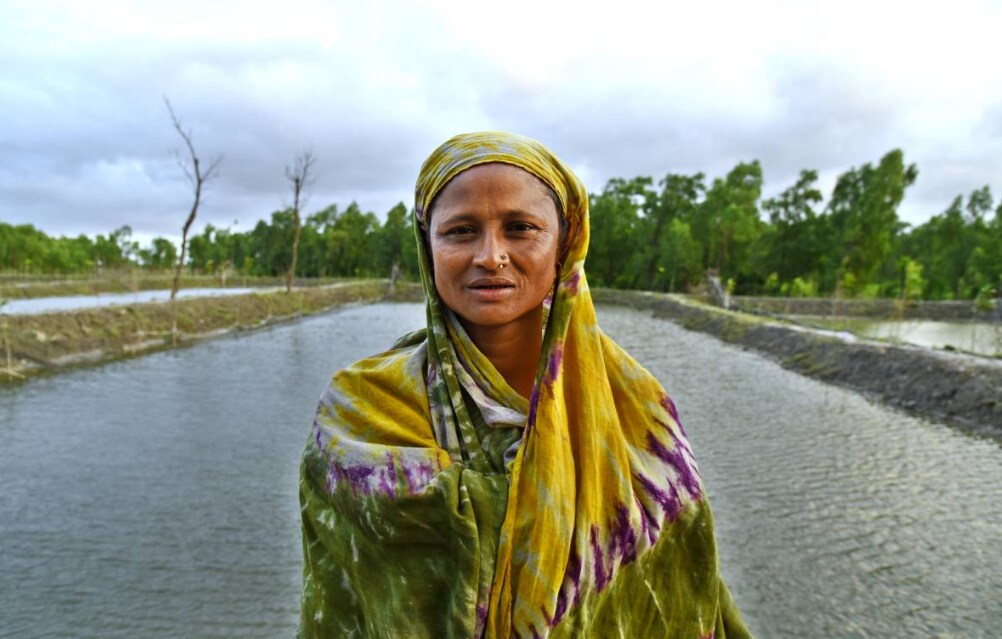 Ferdousi Akter stands in front of a fish pond on land she got on a 10-year lease from the Bangladesh Forest Department, Hatiya Island, Noakhali District, Bangladesh, Oct. 22, 2018,