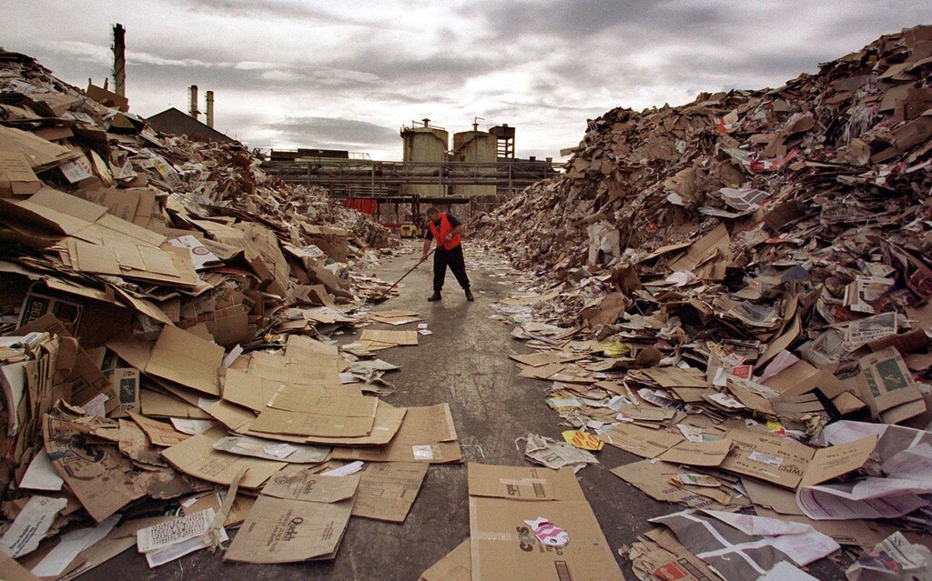 A worker cleans a path through the tonnes of waste paper awaiting recycling at Australia's largest paper recycling mill in Sydney. Prices for recycling paper, plastic and bottles have fallen so far in the last year that Australia is paying Indonesia to accept some of the A$100 million (US$76 million) a year industry. Picture taken 6JUN97. - PBEAHUMMQBD